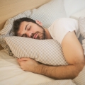 Image of a man peacefully sleeping on a bed, highlighting Thai massage benefits, including improved sleep quality, relaxation, and enhanced overall well-being.