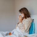 Image of a woman sitting in bed drinking tea, highlighting Thai massage benefits, including boosting the immune system, reducing stress, and promoting overall health and wellness.