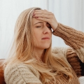 Image of a woman holding her forehead in discomfort, highlighting Thai massage benefits, including relief from chronic headaches, tension reduction, and improved mental clarity.