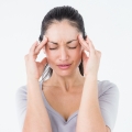 Image of a woman holding her temples in discomfort, highlighting Thai massage benefits, including effective migraine relief, tension reduction, and improved mental relaxation.