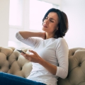 Image of a woman holding her neck and wincing in pain, highlighting Thai massage benefits, including effective pain management and relief for improved overall well-being.