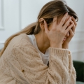 Image of a woman holding her head in distress, highlighting Thai massage benefits, including effective stress reduction, relaxation, and improved mental well-being.